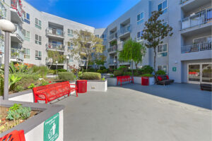 Outdoor Courtyard Area, Red Benches, Surrounding Landscaping, Trees, Balconies above.