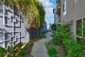 Outdoor Walkway, surrounding landscaping, wall sculptures and ivy. balconies above walkway.